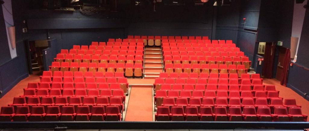 Red seating in the single raked, central aisled auditorium of Chorley Theatre.